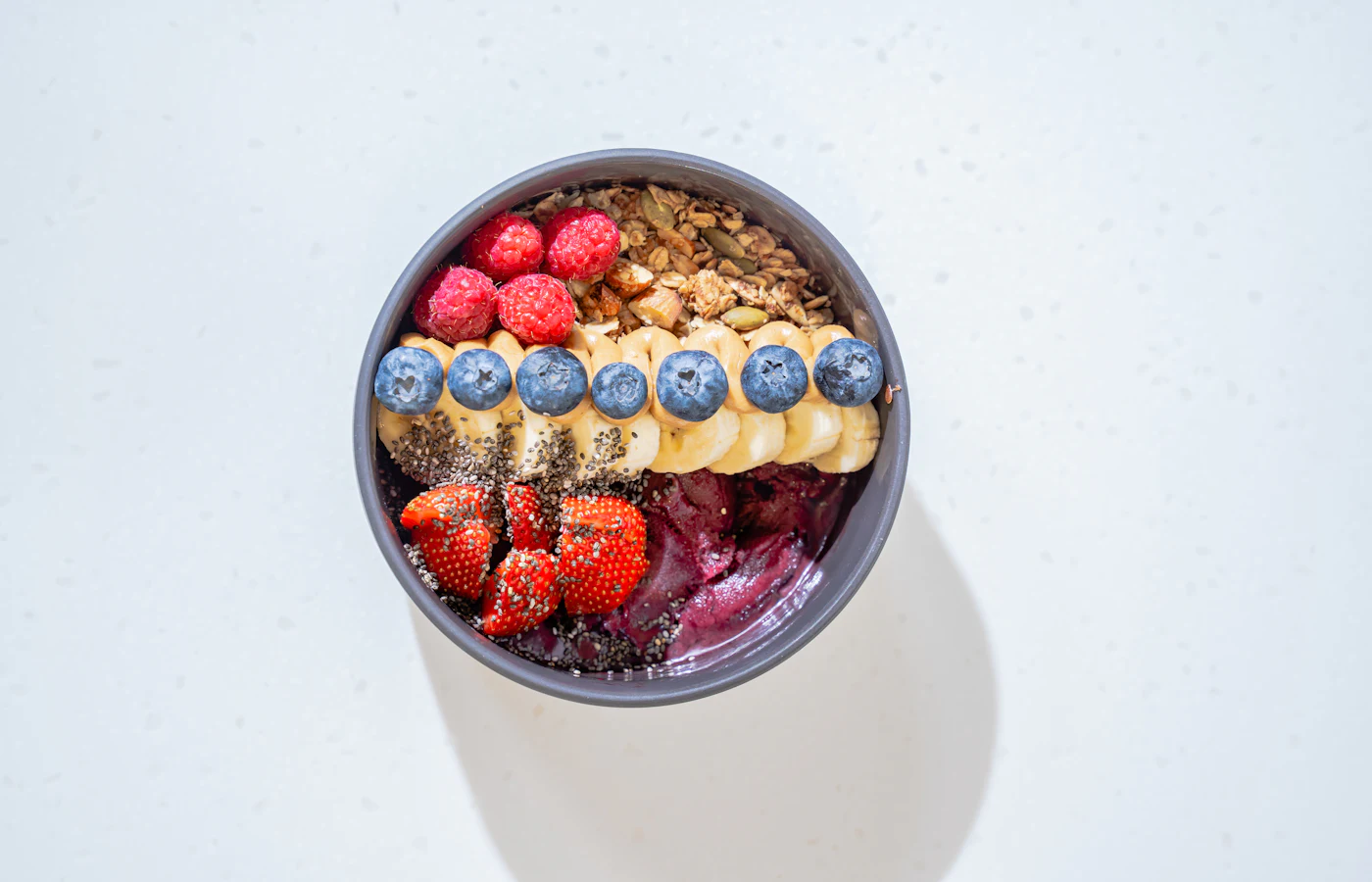 Eine Schale Müsli mit Beeren, Banane und Samen von oben